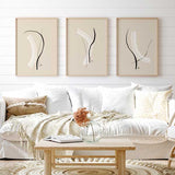 conjunto de tres cuadros minimalistas y abstratos con ilustraciones de trazos blancos y negros sobre un fondo beige crema. Ideal para ambientes modernos, salones y salas de estar - idea de decoración con cuadros