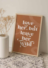 decoración con cuadros, ideas - Cuadro con frase "Love her, but leave her wild" con fondo rojizo y naranja